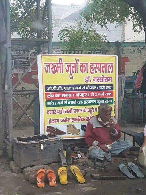 Narsi Ram working at his stall with the billboard behind him which reads 'Zakhmi Jooton Ka Hospital'. (Source: Twitter/Anand Mahindra)